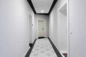 波兹南Loft Apartments Poznań的走廊设有白色墙壁和黑白瓷砖地板。