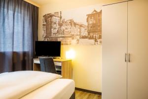 特里尔Schroeders City-Style-Hotel的一间卧室配有一张床和一张书桌及电视