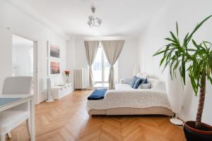 维也纳阿尔加维市中心奥佩拉大街公寓的白色卧室配有一张大床和盆栽植物
