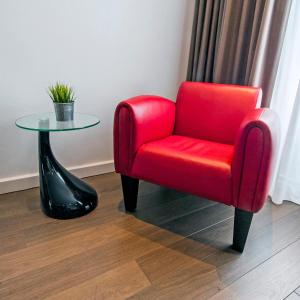 贝亨奥普佐姆City Hotel Bergen op Zoom的一张红椅子坐在玻璃桌旁