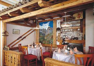 莫尔韦诺阿尔卑斯酒店的餐厅设有桌椅,墙上挂有绘画作品