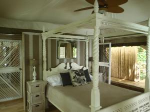 卢甘维尔希登湾生态度假酒店的卧室配有白色的床和吊扇