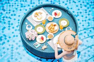三亚三亚悦榕庄(私享沙滩，早餐至14点)的坐在餐桌旁带食物的戴帽子的女人