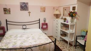 滨海波利尼亚诺Bed and Breakfast Dolce Sorriso的一间卧室配有一张床和一个墙上十字架的梳妆台