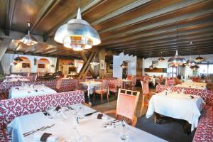 塞尔瓦迪加尔代纳山谷康多尔酒店的用餐室配有白色的桌子和红色的椅子