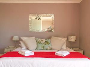 梅森堡矢车菊宾馆的一间卧室配有一张带红色毯子和镜子的床