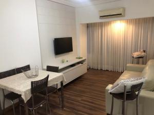 弗洛里亚诺波利斯Apto aconchegante 100m Shopping Beiramar的客厅配有桌子、沙发和电视
