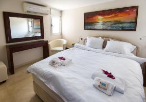 纳哈里亚Ha-aliya Sea View的卧室配有白色床、两条毛巾和镜子