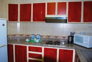 艾恩绿色木巴匝拉木屋的厨房配有红色橱柜和白色微波炉