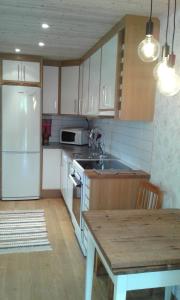 TrÃ¤slÃ¶vslÃ¤geStuga i Gamla-köpstad的厨房配有白色冰箱和木桌