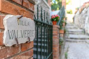 陶尔米纳Villa Valverde Apartments e B&B的砖墙边的标志,有别墅的花边