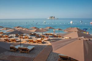佩特罗瓦纳莫鲁Hotel Riva by Aycon的海滩上设有遮阳伞和椅子,还有大海