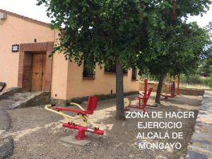 Alcalá de MoncayoCasa Rural La Tejada的一组红色椅子坐在树旁