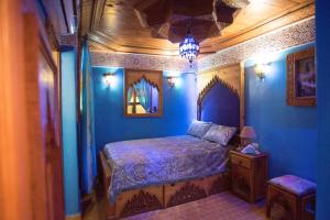 梅克内斯Riad Mehdi Meknès的一间拥有蓝色墙壁的卧室,配有一张床和一张桌子