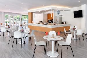 拉克鲁斯拉克鲁斯港特内里费阳光酒店的一间带白色桌椅的餐厅和一间厨房