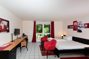 魏玛魏玛艺术酒店的一间卧室配有两张床、一张桌子和红色椅子