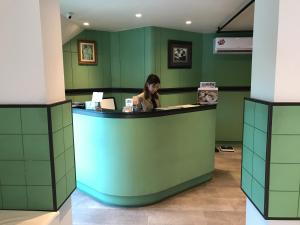 莱卡邦L42素万那普机场旅馆的坐在绿色房间里柜台上的女人