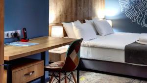 埃里温Hotel Alpha的一间卧室配有一张床和一张带一张桌子的桌子,一张桌子上配有一张高质量的床铺。