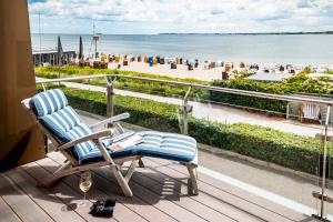 施特兰德Hotel Apartments Büngers - Mein Refugium am Meer mit Sommerstrandkorb的海滩景阳台的摇椅