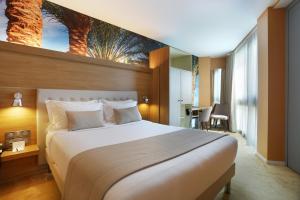 巴黎乔丁斯德玛德莫赛勒酒店及Spa的卧室配有一张大床,墙上挂有绘画作品
