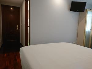 拉科鲁尼亚Saudade Hostal Cafetería的卧室配有白色的床和电视。