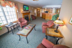 Meadow LakeWoodland Inn的客厅配有粉红色的椅子和桌子