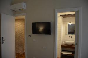 那不勒斯Palazzo Pignatelli的一间带水槽的浴室和墙上的电视