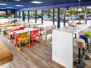 南安普敦南安普敦中心宜必思快捷酒店的餐厅设有多彩的桌椅和窗户。