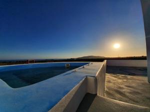 安坡里奥圣托里尼Villa Therme Athena的一座享有日落美景的房屋屋顶上的游泳池