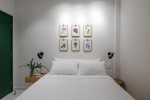 胡志明市Botanist Lab Minihotel by CIRCADIAN的卧室配有一张白色床,墙上挂有4张照片
