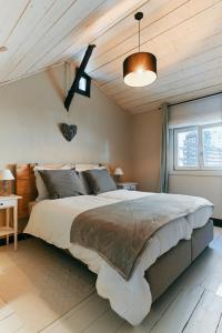 马尔梅迪Le Petit Gretedar的一间卧室设有一张大床和木制天花板