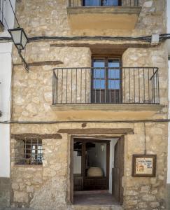 Chiva de MorellaAlojamiento Rural Font del Roser的石头建筑,设有门和阳台