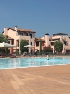 佩斯基耶拉德加达Esclusivo trilocale con piscina al Garda Resort Village的在有建筑背景的游泳池游泳的人