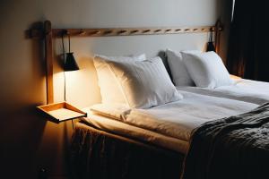 DonsöHotel Isbolaget的一张带白色枕头的床,靠在灯边