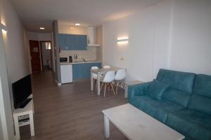 波蒂纳茨Apartamentos Portinatx Sea View的一间带蓝色沙发的客厅和一间厨房