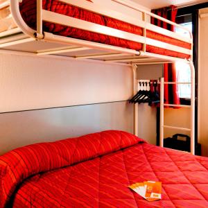 特里尼亚克普瑞米尔圣纳扎尔特里纳克经典酒店的一间卧室配有一张红色棉被的床