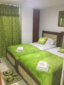 里奥阿查Hotel Atardecer Guajiro的配有两张床铺的客房提供绿色床单和毛巾
