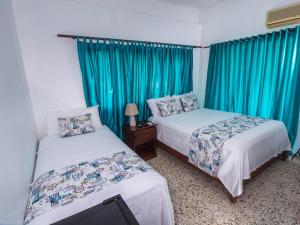 圣多明各B&M Setup Hotels的配有蓝色窗帘的客房内的两张床