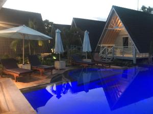 蓝梦岛D'Yuki Huts Lembongan的房屋旁的游泳池配有椅子和遮阳伞