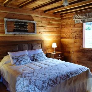 FresiaLodge El Sarao A Una Hora De Puerto Varas的木制客房内的一间卧室,配有一张床