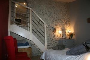 ChâteaudoubleLe domaine des rouges queues的一间卧室设有楼梯和一张带红色椅子的床