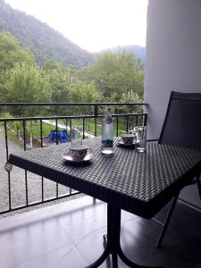 博尔若米Guesthouse Zaqara的阳台上配有带两个盘子的桌子和一瓶水