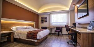 普埃布拉JF Grand Puebla的配有一张床和一张书桌的酒店客房