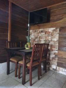 福尔图纳Cabaña Rural el Mirador的一张带椅子的木桌和石墙上的电视