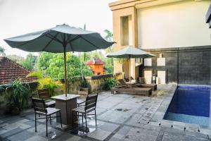 登巴萨普里阿玉酒店的庭院配有桌椅和遮阳伞。