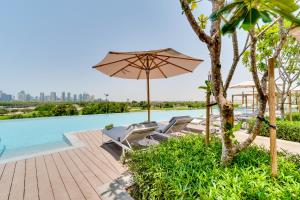 迪拜Vida Emirates Hills Residences的游泳池旁的遮阳伞和躺椅