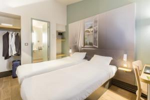 圣埃尔斯B&B HOTEL Montpellier Vendargues的配有镜子的酒店客房内的两张床