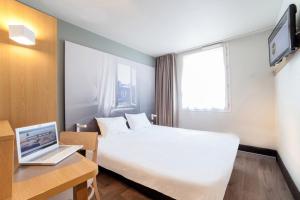 圣埃尔斯B&B HOTEL Montpellier Vendargues的酒店客房配有一张床铺和一张书桌上的笔记本电脑