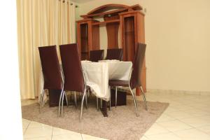 纳库鲁Essy's Apartments Nakuru with pool & GYM的一张桌子、棕色椅子和白色桌布
