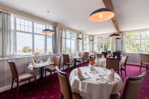 曼海德诺斯菲尔德酒店的餐厅设有白色的桌椅和窗户。